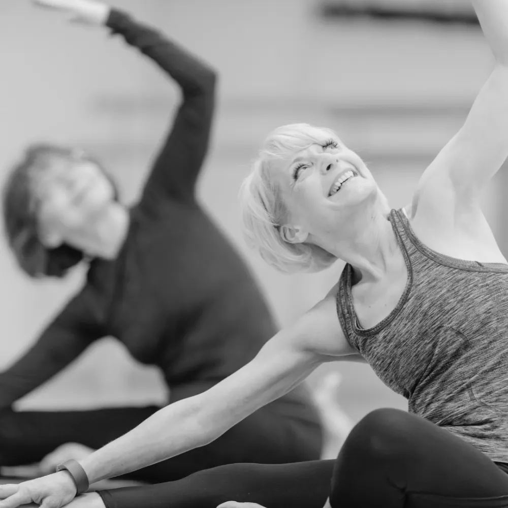 Two older women taking a yoga class